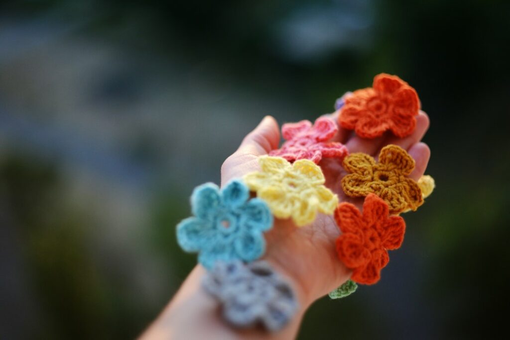 A bunch of colorful crocheted flowers held in one hand