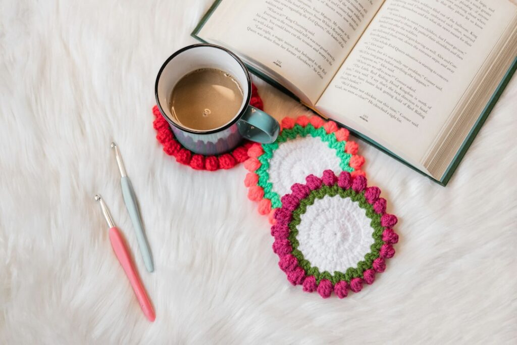 A handmade crochet coaster beside a coffee cup and book