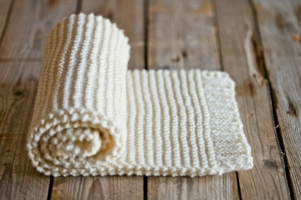 Soft white handmade crochet blanket folded in natural light